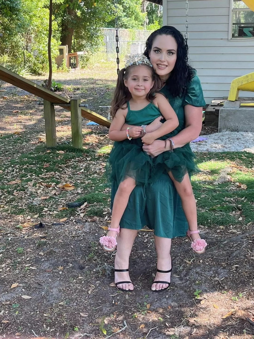 Jessey Bowers holding her daughter in matching green dresses
