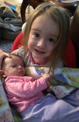 Little girl holding a newborn baby.