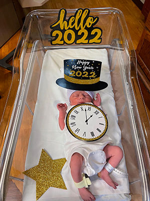 Inside a hospital bassinet, "New Years 2022" holiday decorations surround newborn infant Serenity A’Seanti McCoy.