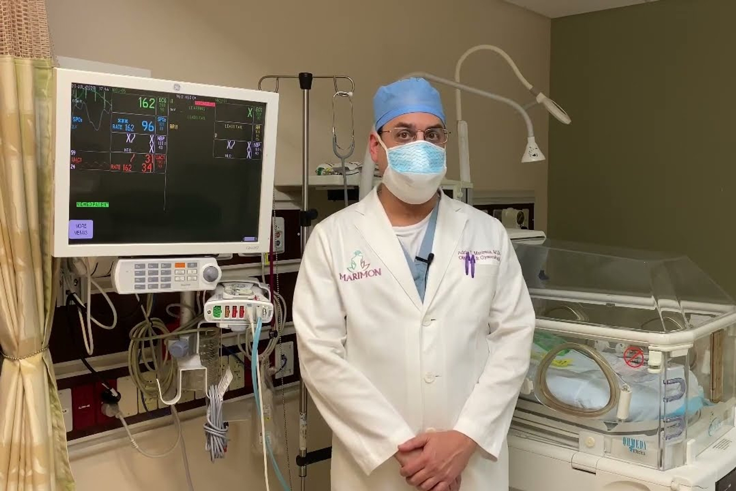 A doctor standing in front of a bed and machines in the nicu