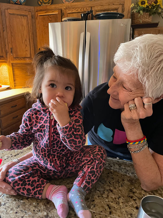 Zona smiles while holding her granddaughter on the kitchen counter.