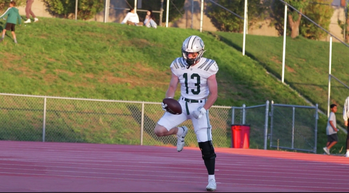 Nash celebrating wearing a white jersey and holding a football