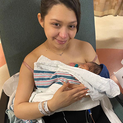 Melisa Villagas smiling while holding her newborn baby Jayden.