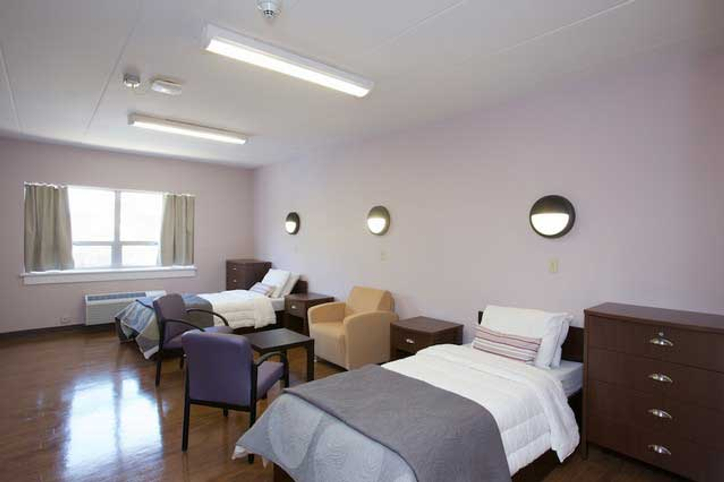 A patient room at Reflections Eating Disorder Treatment Center with two beds, two nightstands, two dressers, and three chairs.