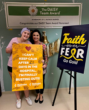 Cancer Survivor Kate Hardaway and her mother holding a sign that says "I can't keep calm after 22 days in the hospital, I'm finally busting out!!!".