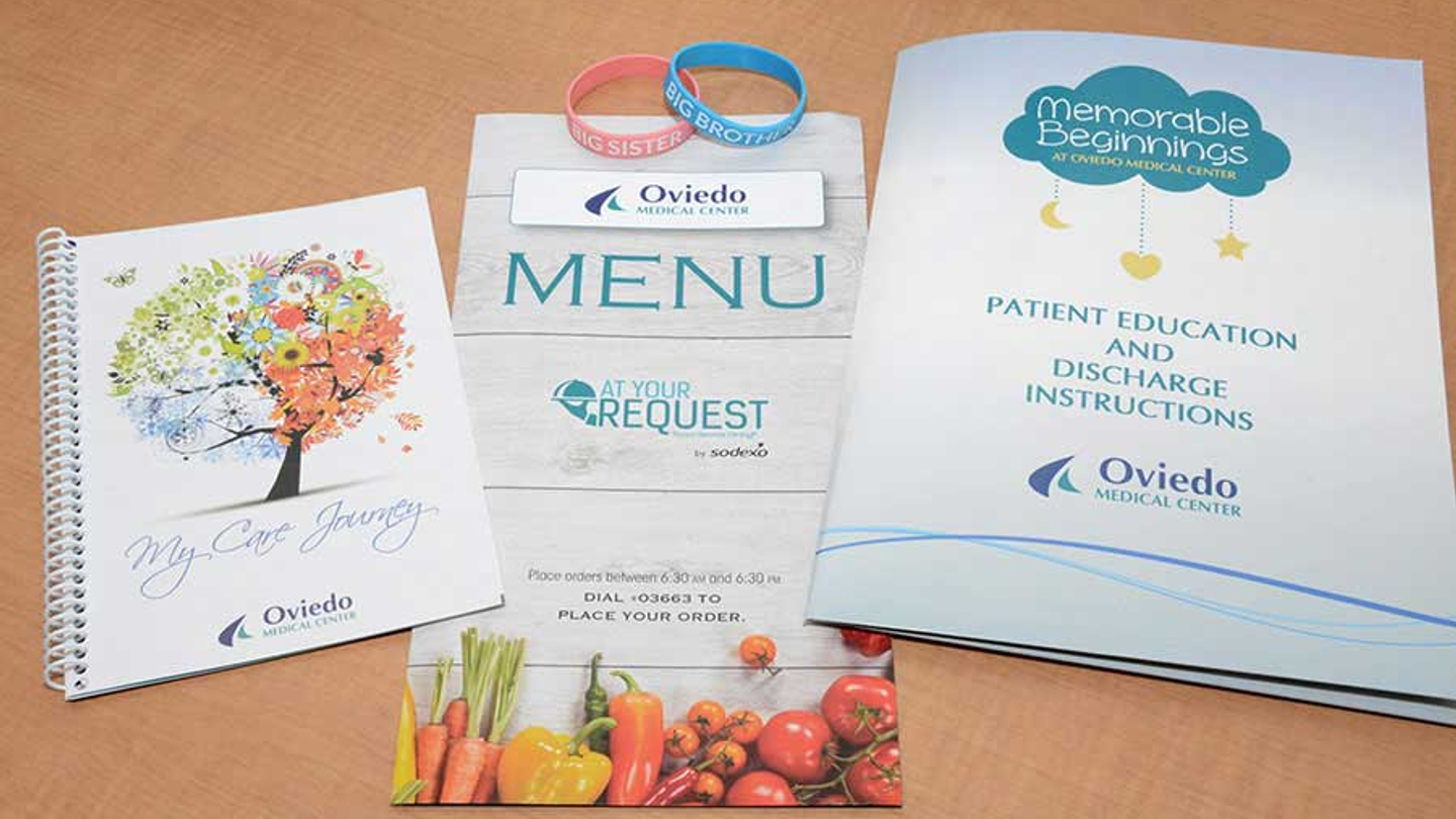 Three patient education pamphlets on a wooded table: My Care Journey, Menu, and Patient Education and Discharge Instructions.