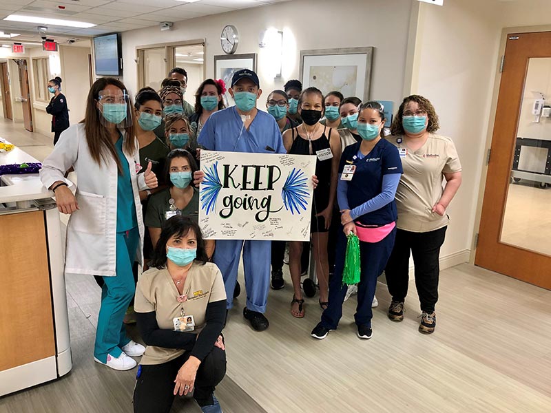 A group of hospital staff and patients holding a sign that says "keep going".