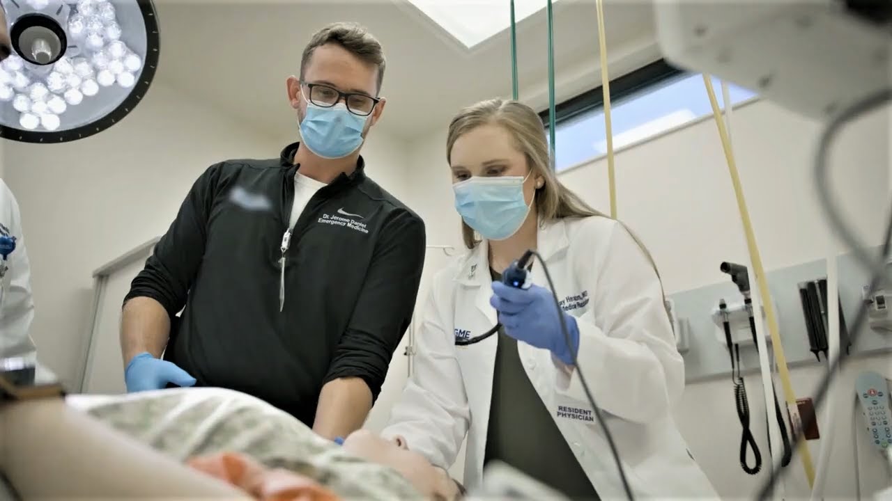 Two Graduate Medical Education students learn how to use medical tools to care for a patient.