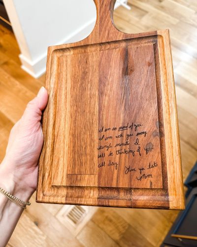 A wooden cutting board with a handwritten message from Megan's mom, Karla.
