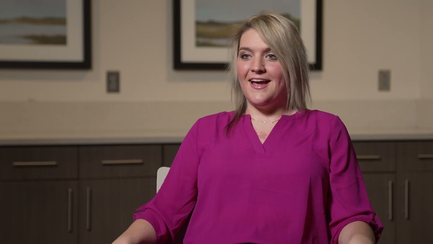 Ashley Topping, smiling and wearing a pink blouse, smiles while discussing her experience as a bariatric surgery patient.