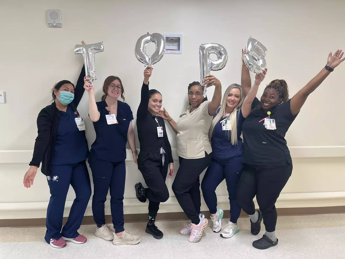 A group of nurses holding balloons that spell out 'Top 5'.