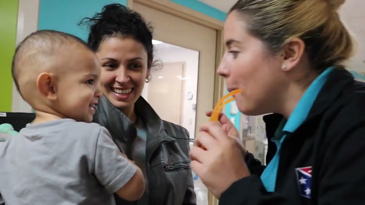 A pediatric nurse interacting with a smiling child and his mother