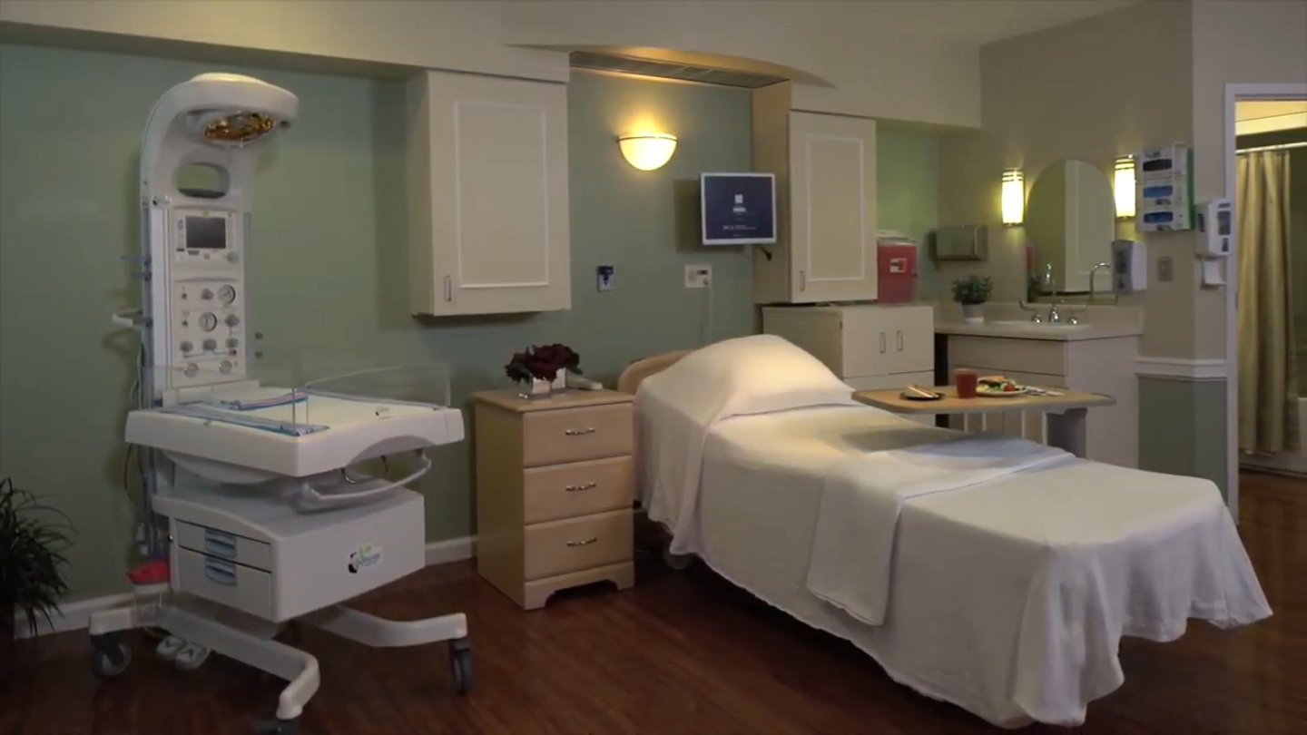 A birthing center room at LewisGale Hospital Montgomery with wood floors, a bed, and a bassinet.