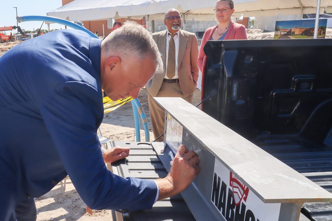 Michael Ehrat, chief executive officer at Fawcett Hospital, signs the steel beam that will be placed into the freestanding emergency room.