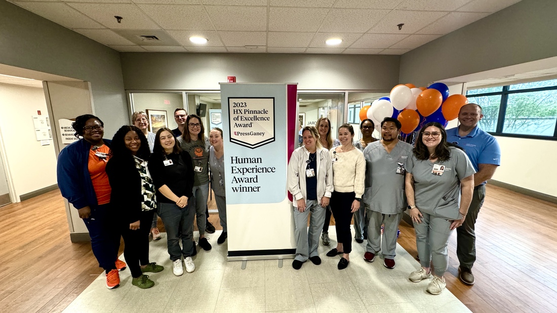 The HCA Florida Largo West Hospital mental health and wellness program team posing with a banner of the award