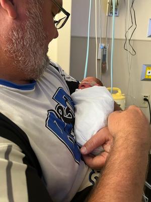 Jonathon holding a swaddled baby Leilani in the NICU