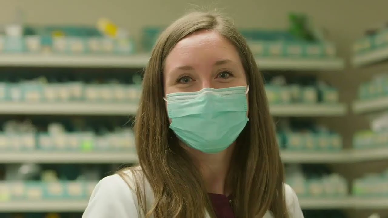 A smiling pharmacist wearing a mask
