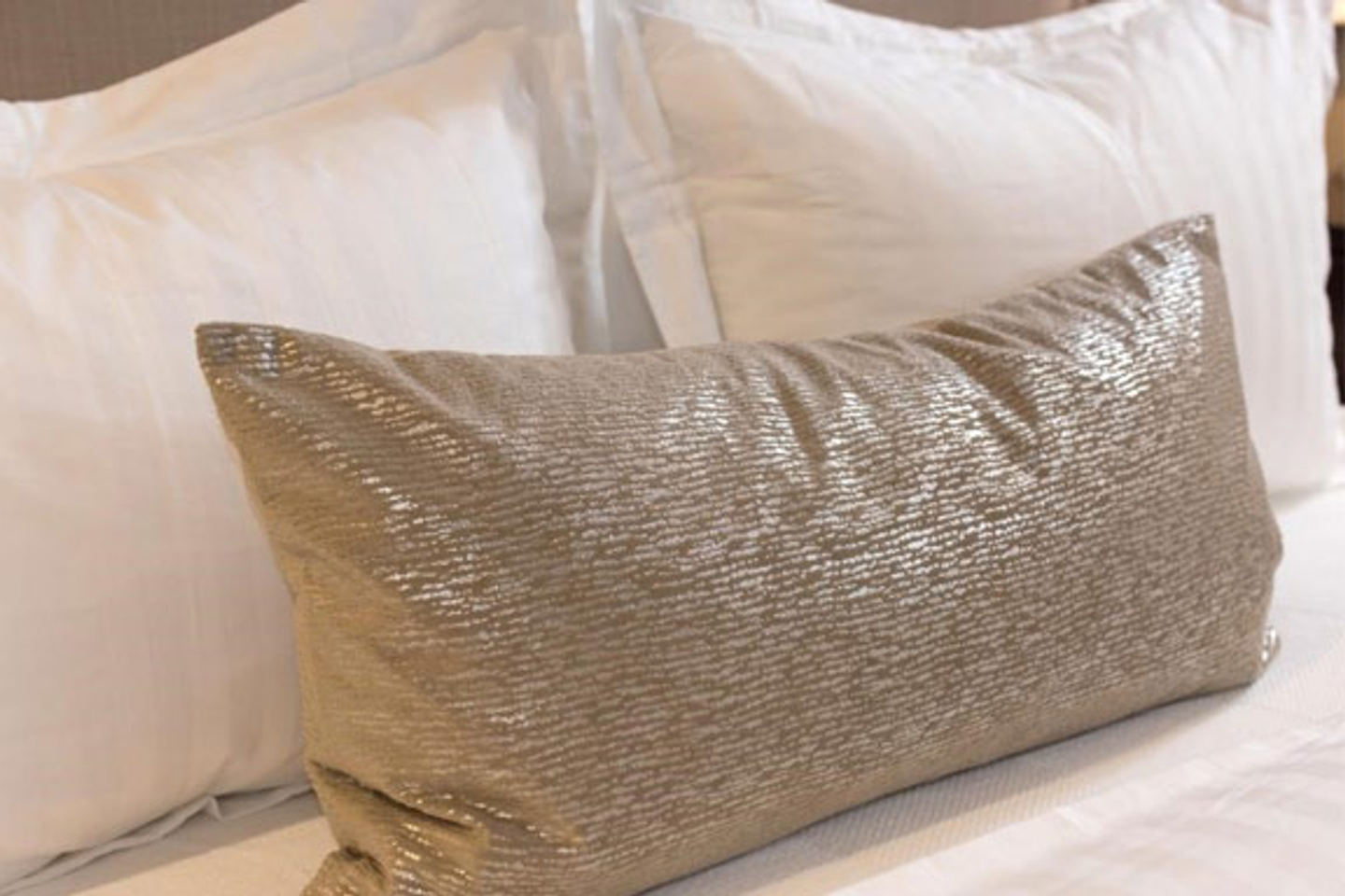 A shimmering beige accent pillow on a Tristar Sleep Center bed.