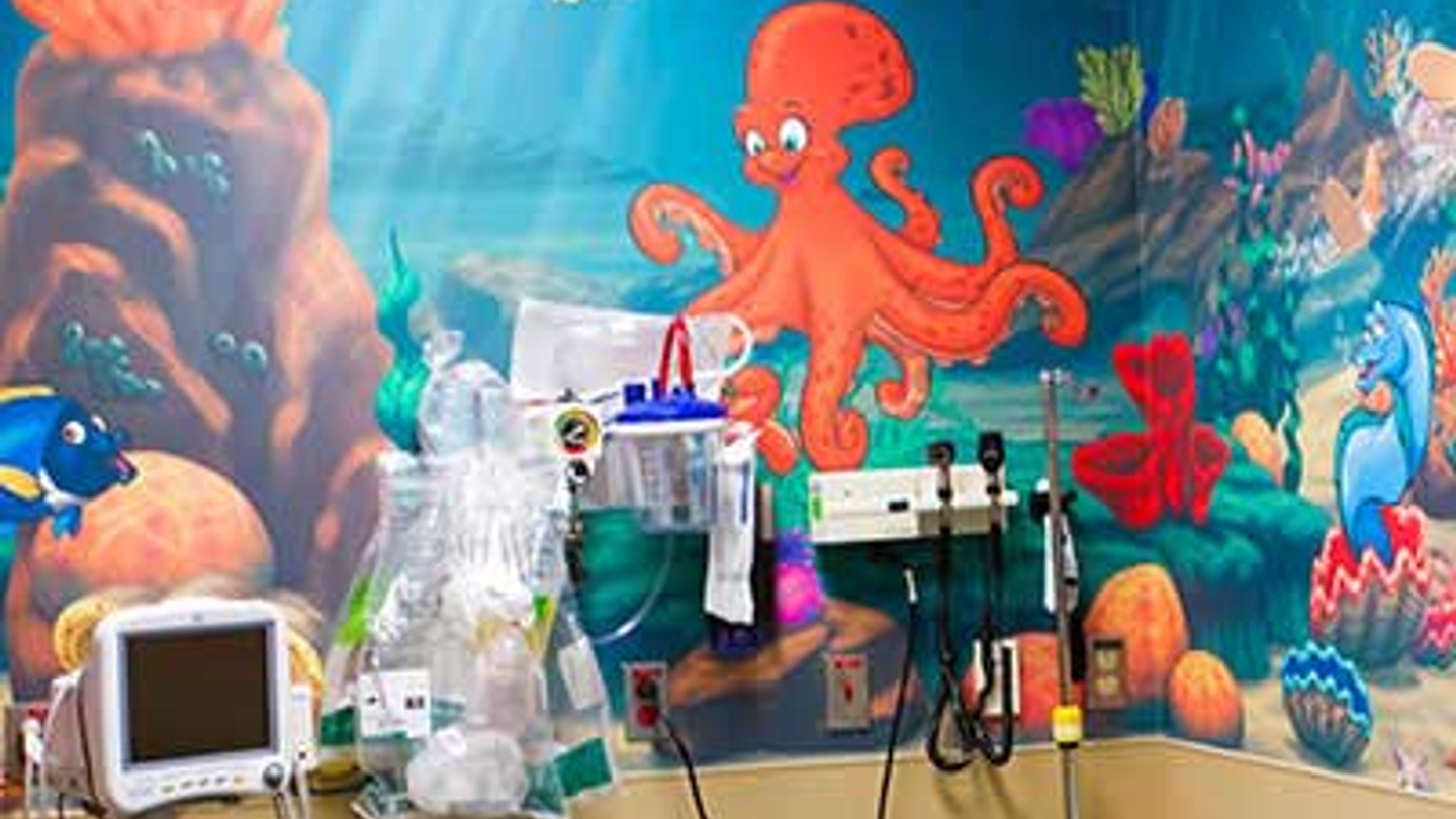 Pediatric emergency care room with a colorful sea themed mural on the wall.