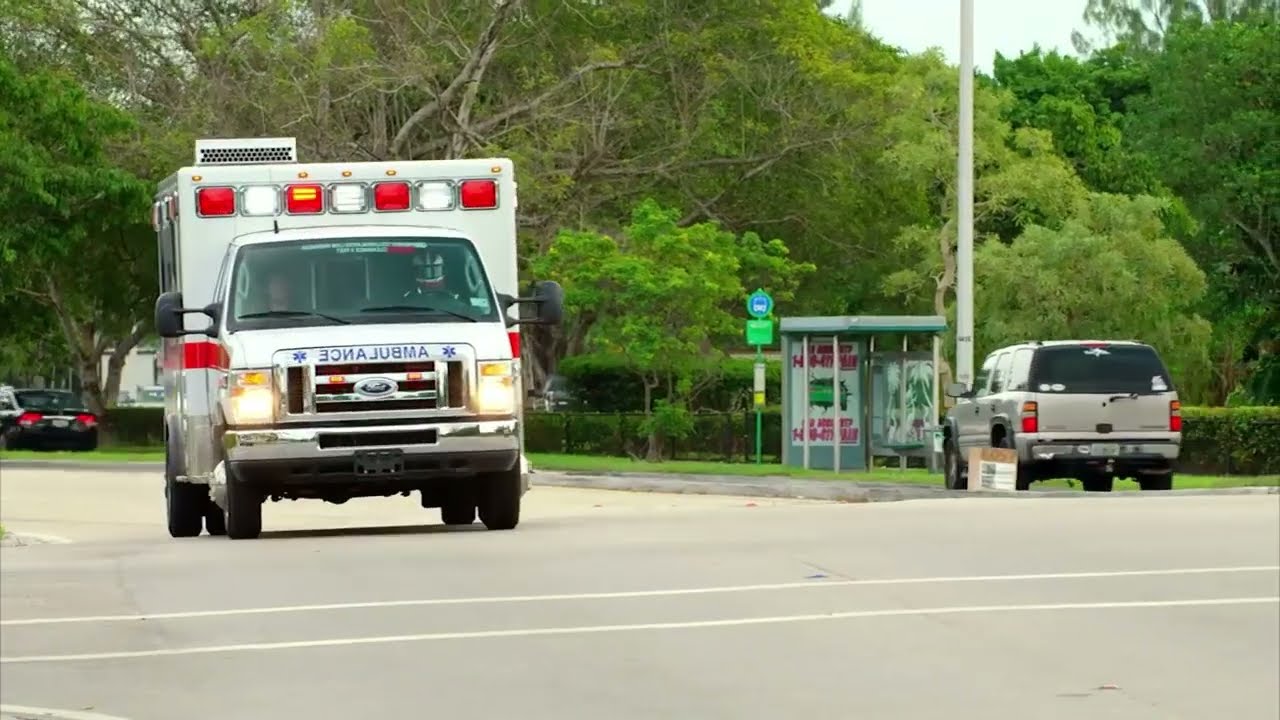 An ambulance driving on the road with it's lights on