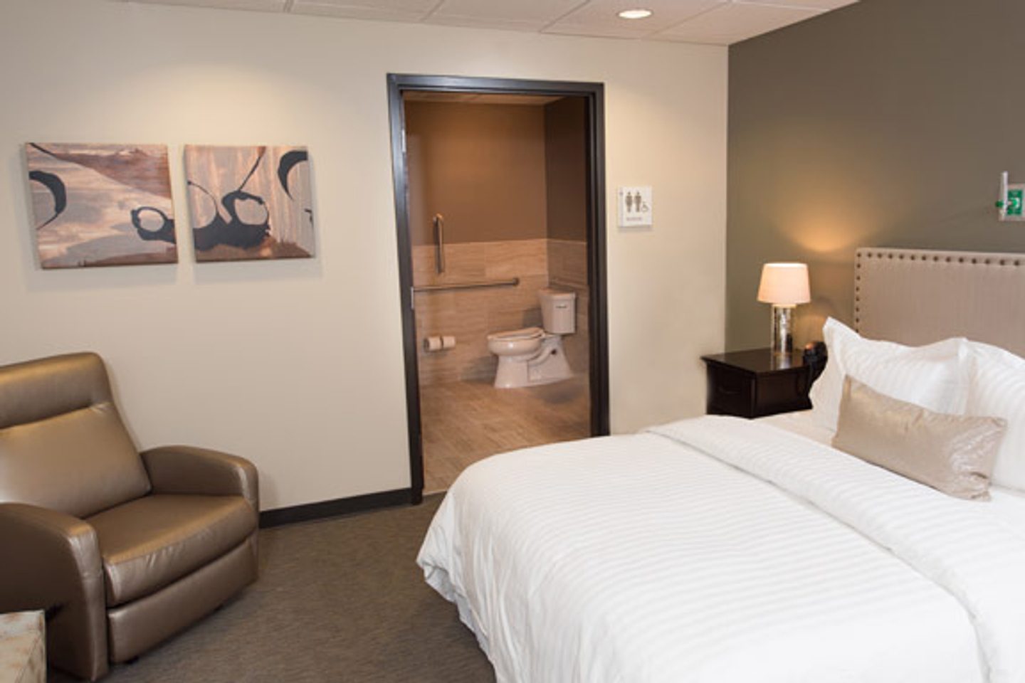 A sleep center room featuring a brown reclining chair, guest bed, and bathroom. 