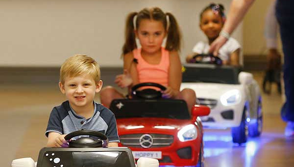 Three kids riding a Hoppymobile, a kid-sized motorized vehicle