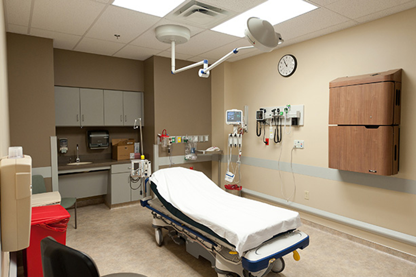 A closer view inside an unoccupied emergency room bed, where a sink, cabinetry and medical equipment are on display.
