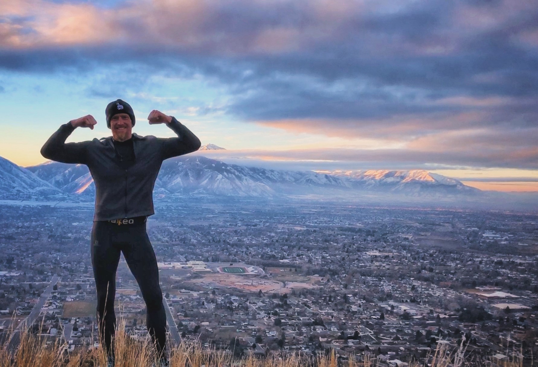 Aaron Jensen flexing his biceps in front of a mountain.