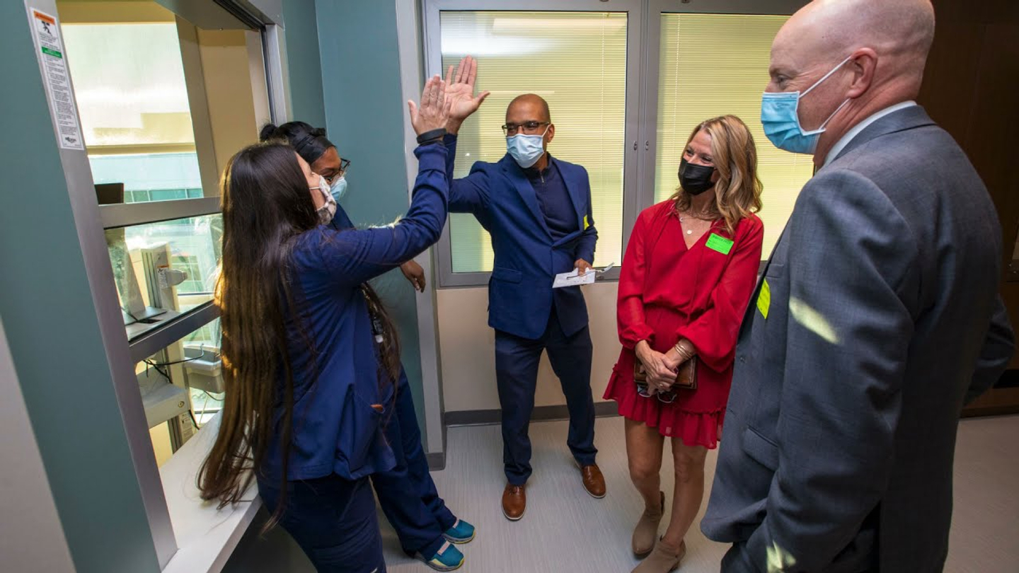 Hospital staff members wearing masks high-five each other in celebration of the ribbon cutting at StoneSprings Hospital Center for the new behavioral health center.
