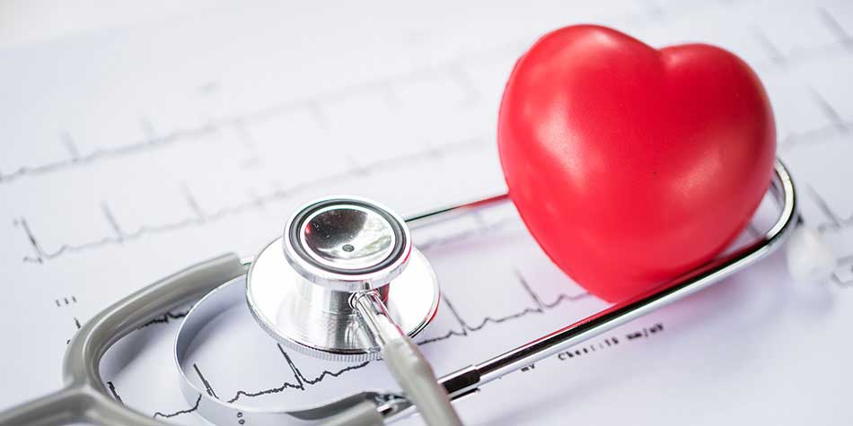 A plastic red heart and silver stereoscope are placed on top of heart monitor readout.
