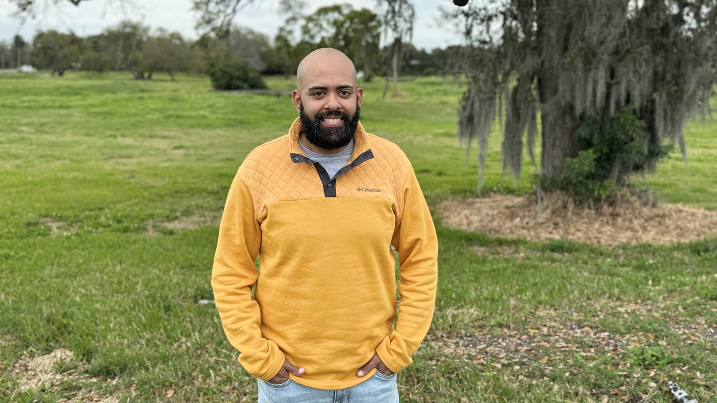 Anthony Moreta standing near a tree in a field.