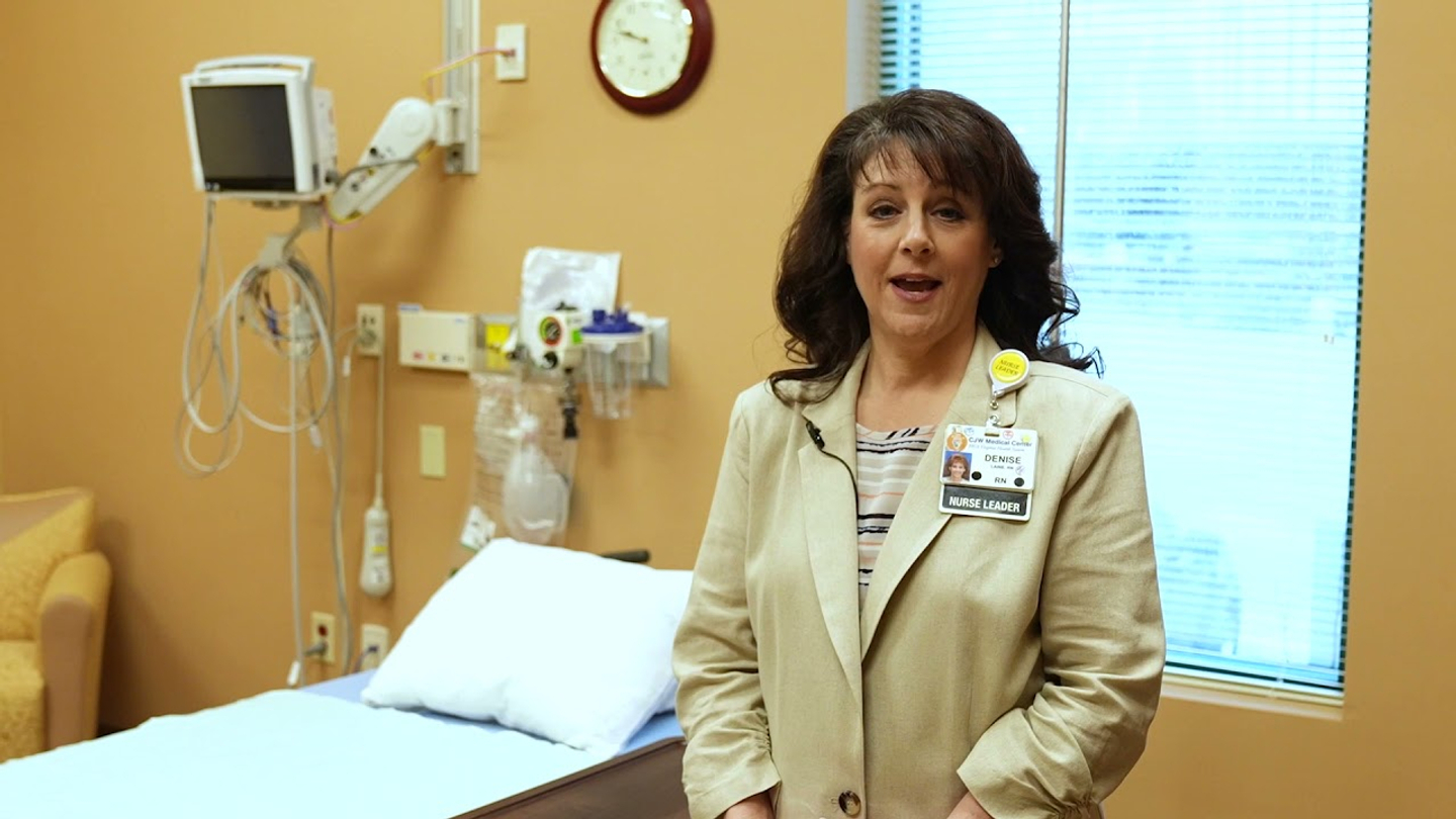Denise Laine, MR Focused Ultrasound Nurse Navigator, standing next to a hospital bed while she discusses treatment pre- and post-op experiences.