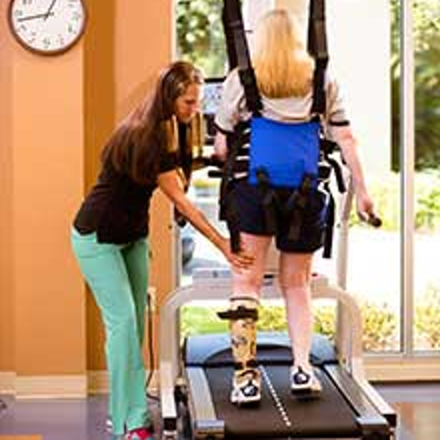 Physical therapist assisting a patient on a treadmill.