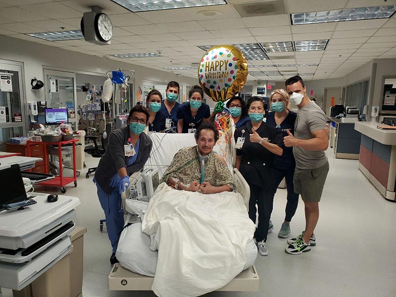 A group of hospital staff gathered around Carlos Gonzalez with a happy birthday balloon