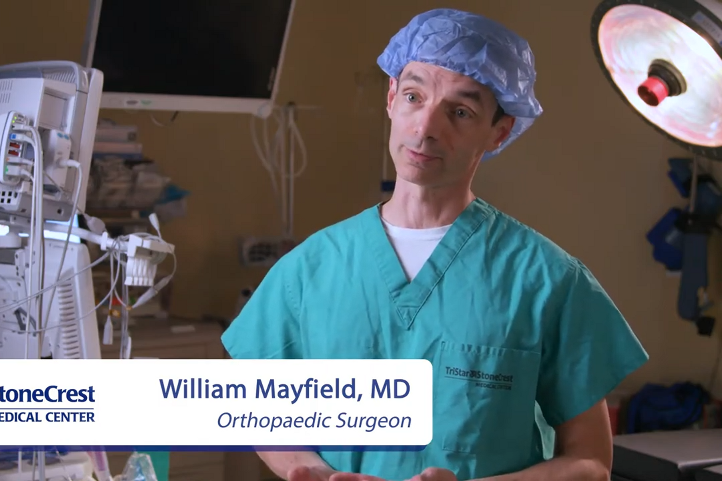 William Mayfield, M.D., standing in an operating room, wearing surgical scrubs.