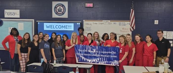 Hospital staff and students pose with banner.
