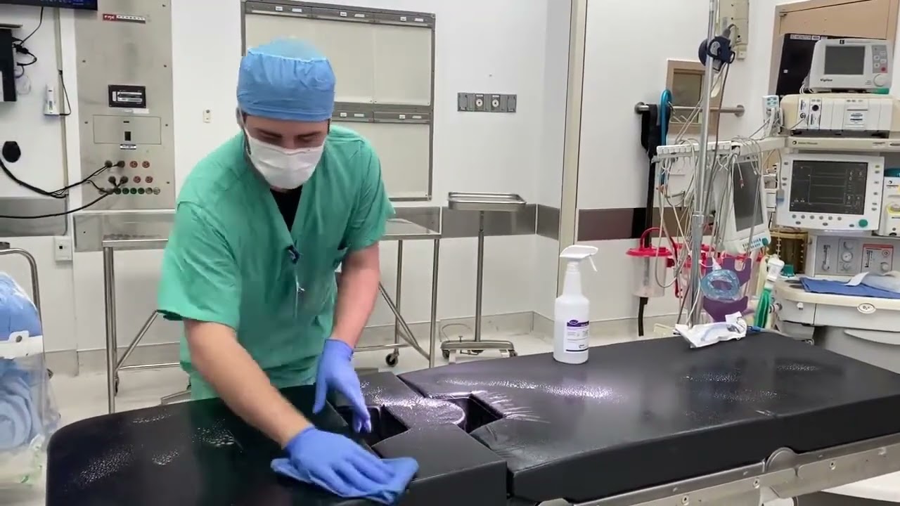 A surgery technician cleans and sterilizes a surgery bed in an operating room.