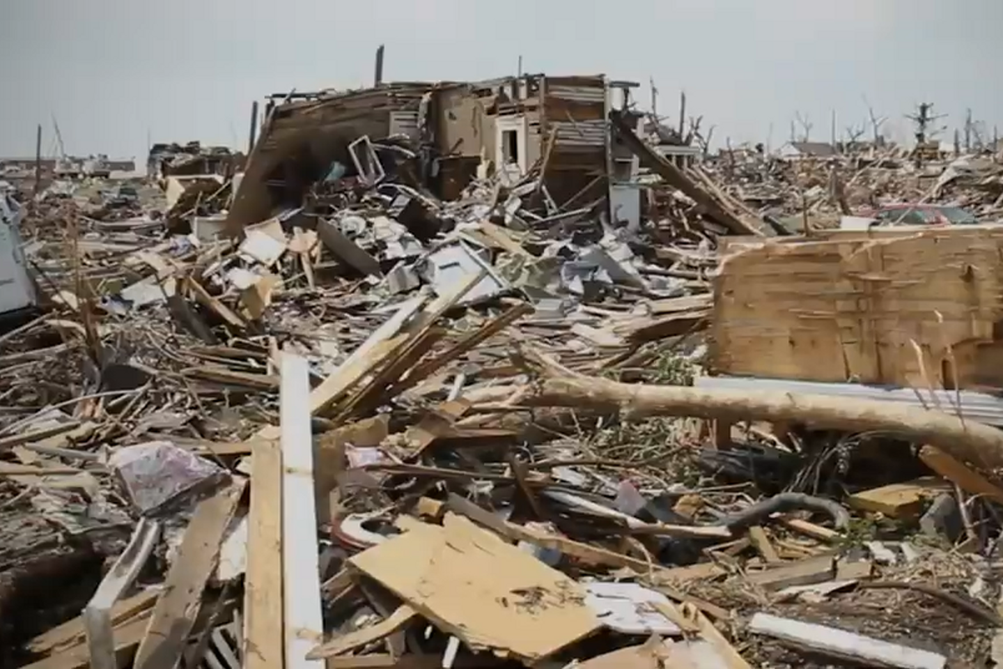 Tornado destruction is seen with a crushed truck and demolished homes. 