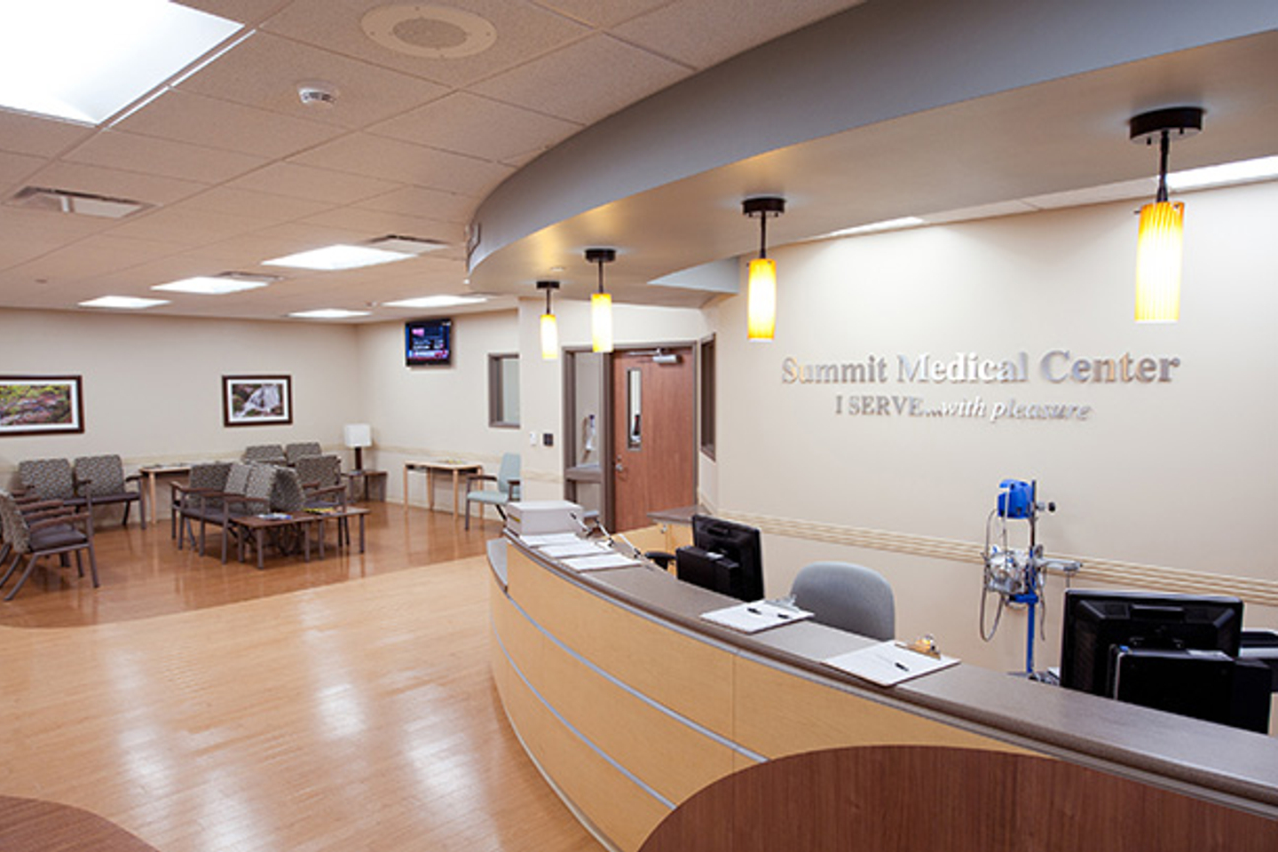 The waiting room at Tristar Summit Medical Center is seen with several grey chairs in the background and a reception desk area to the right. 