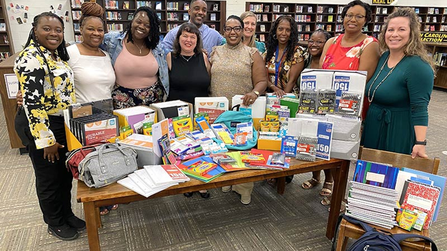 A group of volunteers standing in front of a table full of donated supplies.