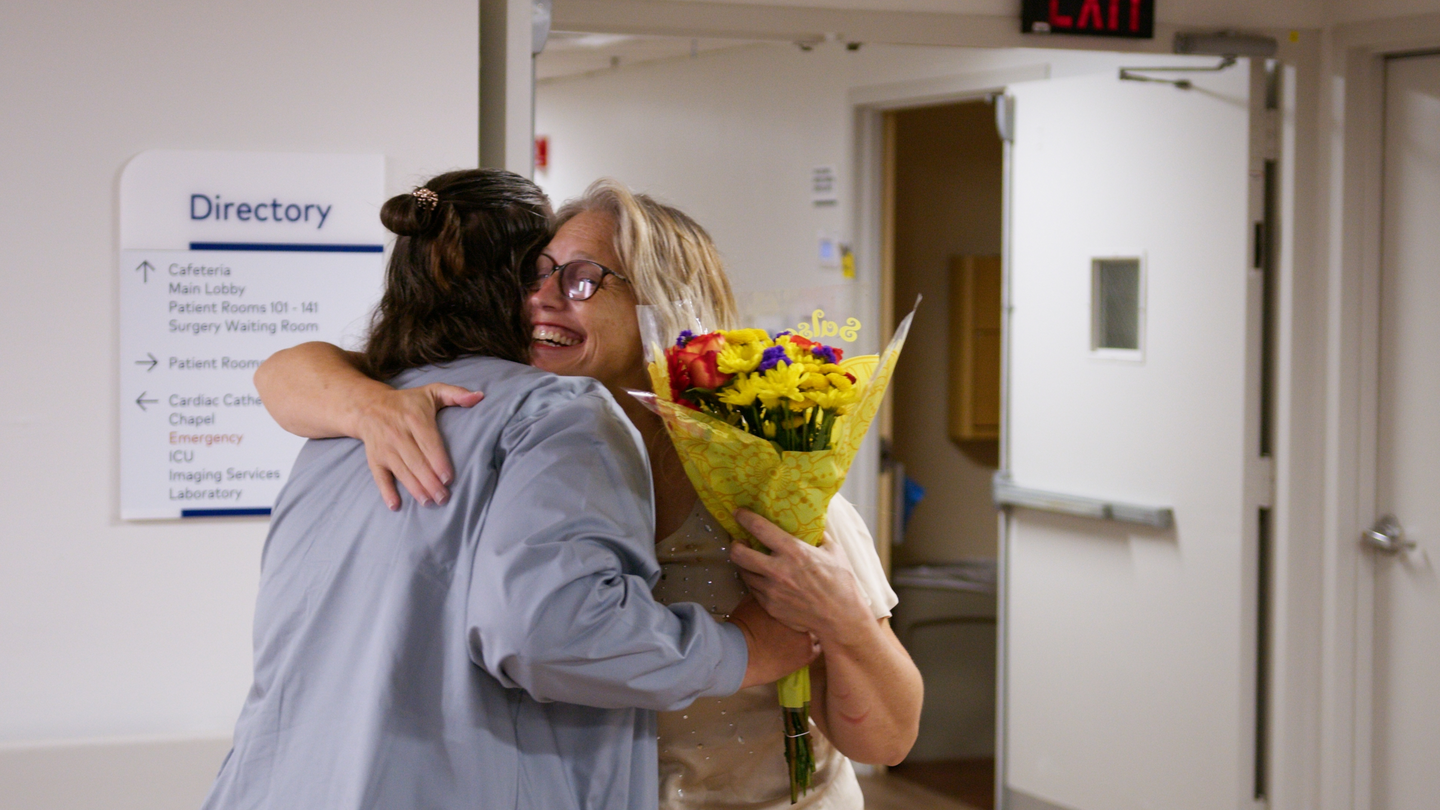 Kimberly Cansler with flowers hugs a nurse who cared for her in hospital