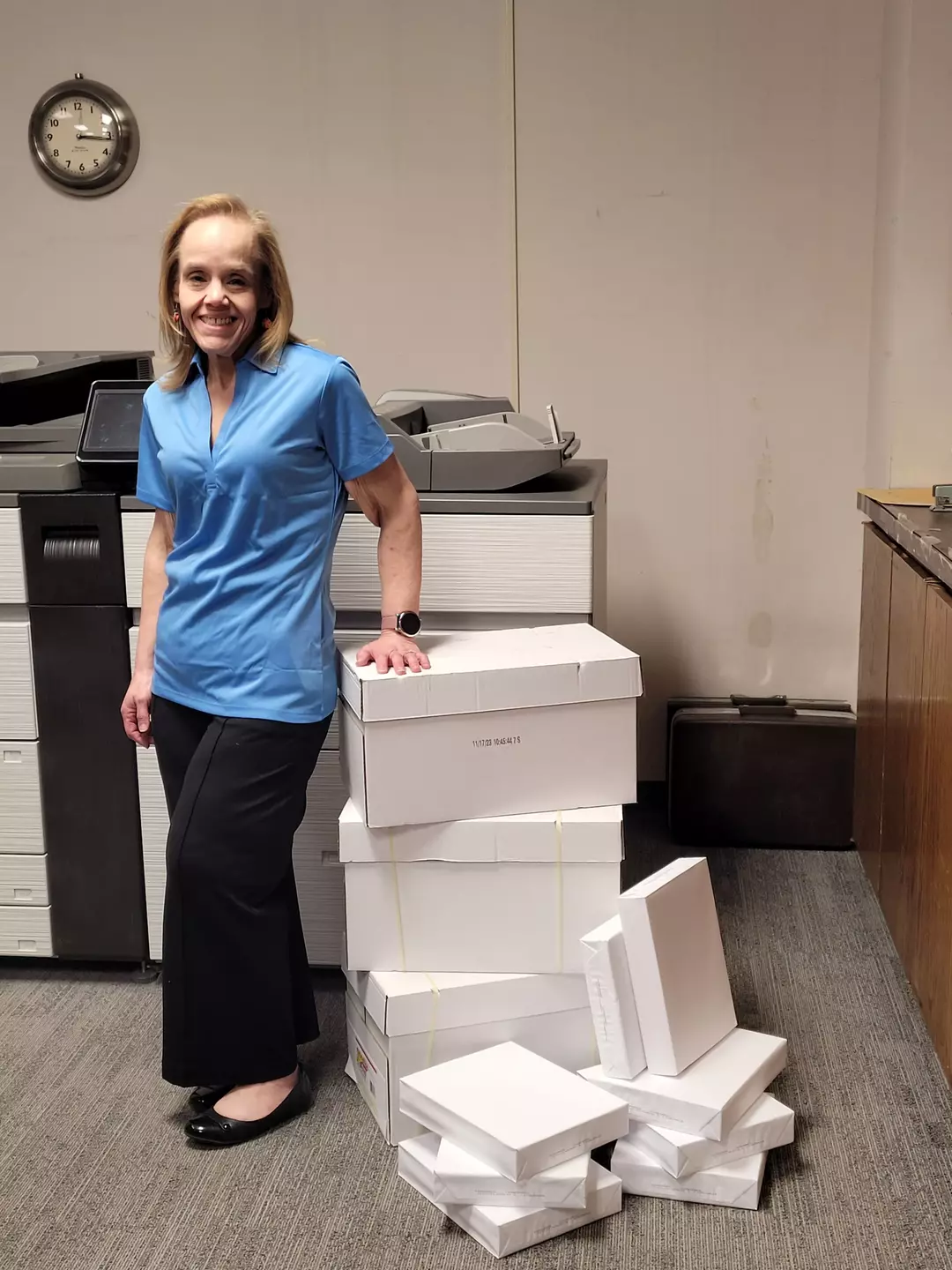 Helen Phelps standing beside stacks of copy paper