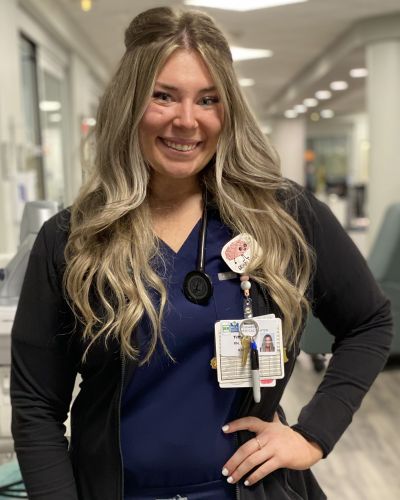 Megan O'Malley smiles while wearing navy blue nursing scrubs at the hospital.