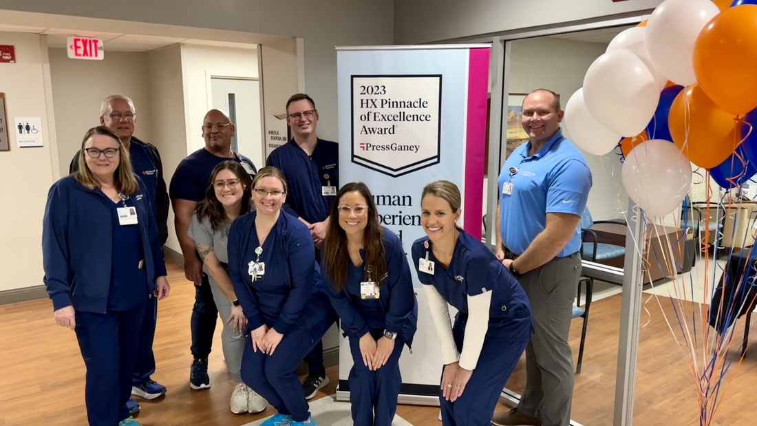 A close-up of the mental health and wellness program team, who provide top 5% for patient experience, posing with the award banner