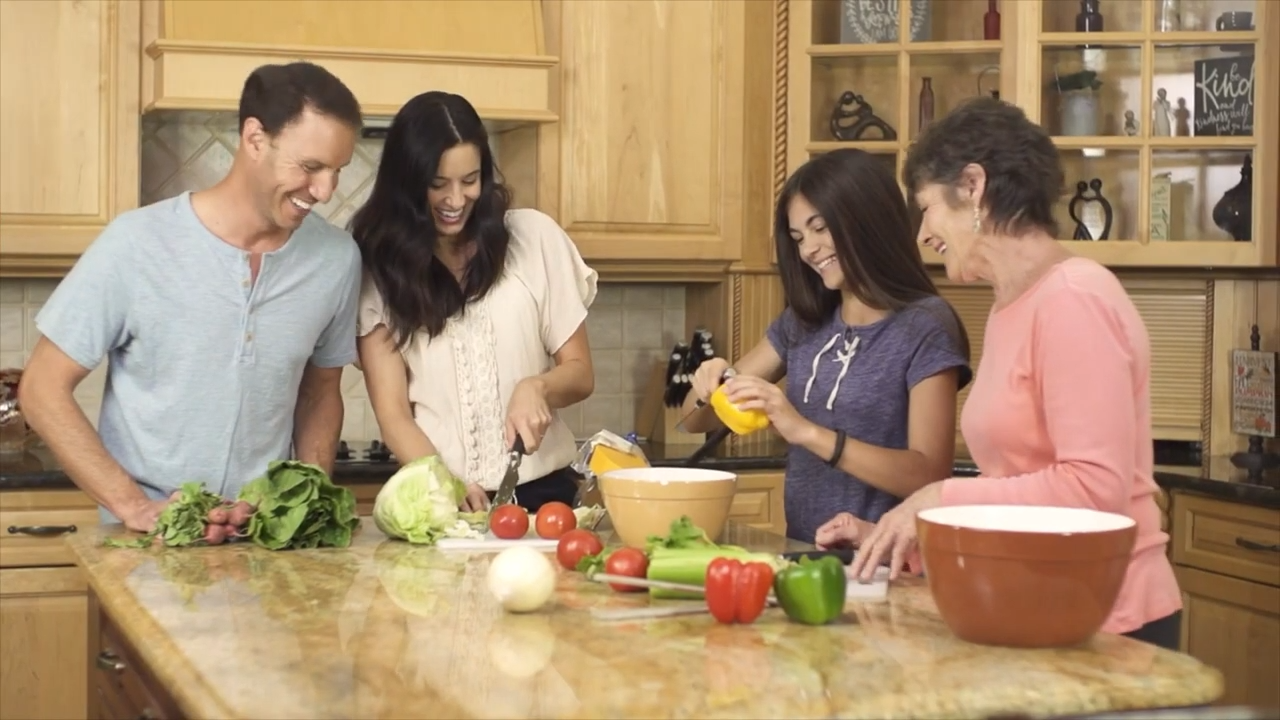 A family cuts vegetables for a meal. 