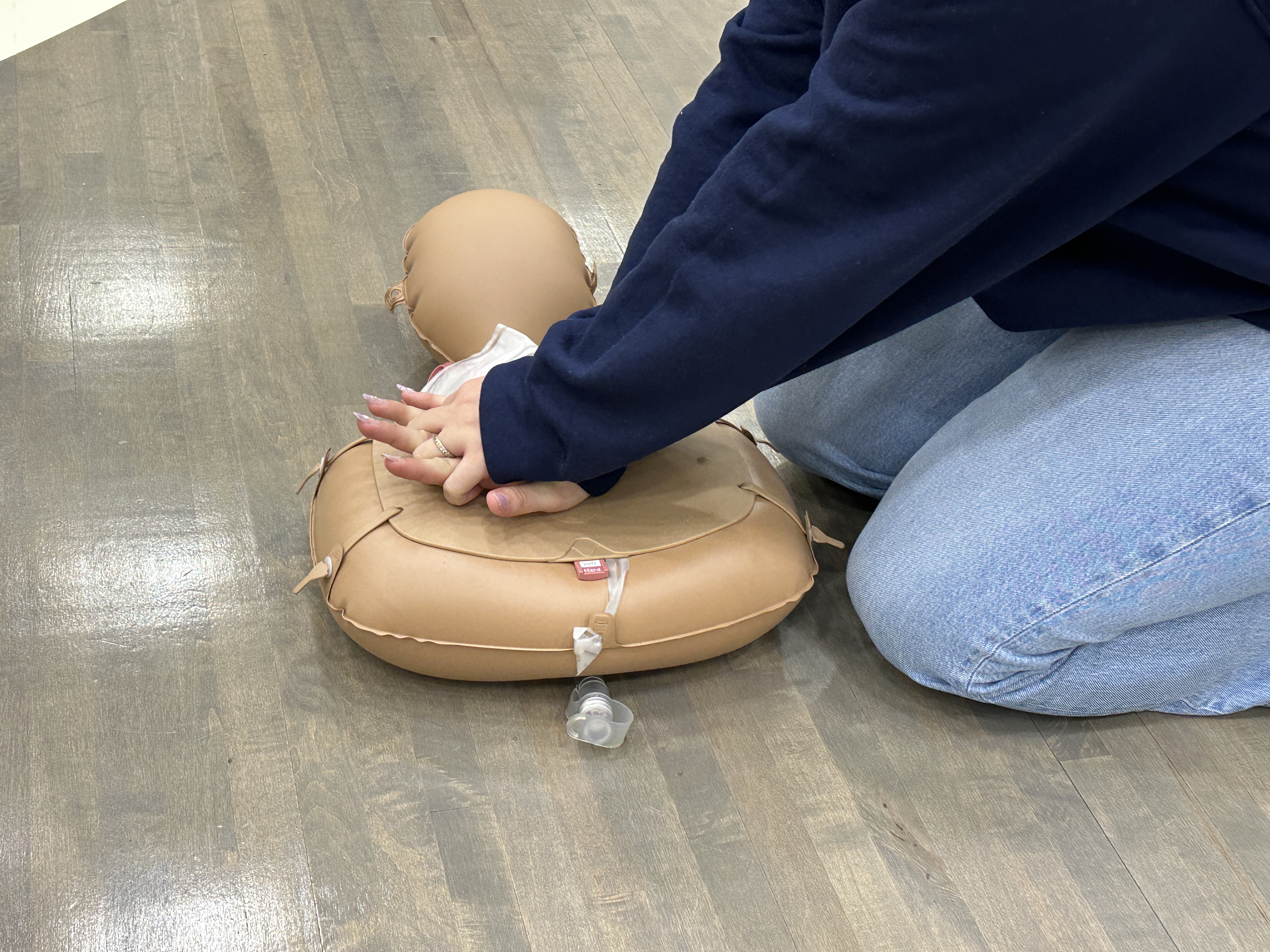 Student practices CPR on practice dummy.