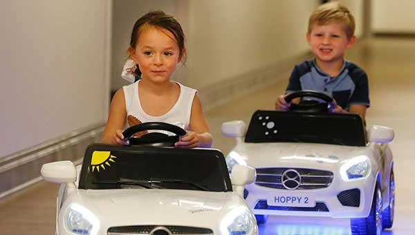 Two kids riding a Hoppymobile, a kid-sized motorized vehicle
