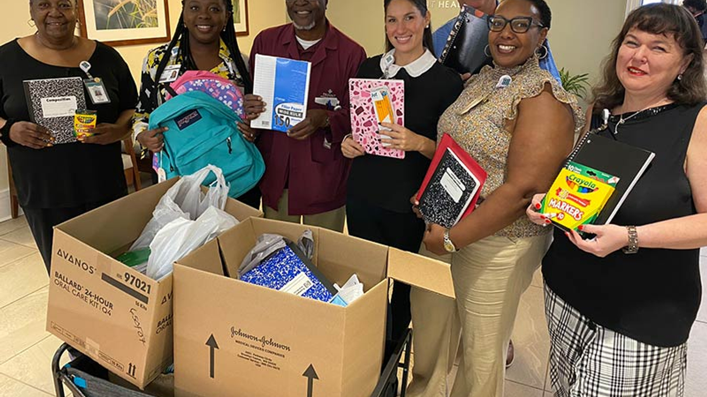 Volunteers holding up donated supplies for Goose Creek High School.