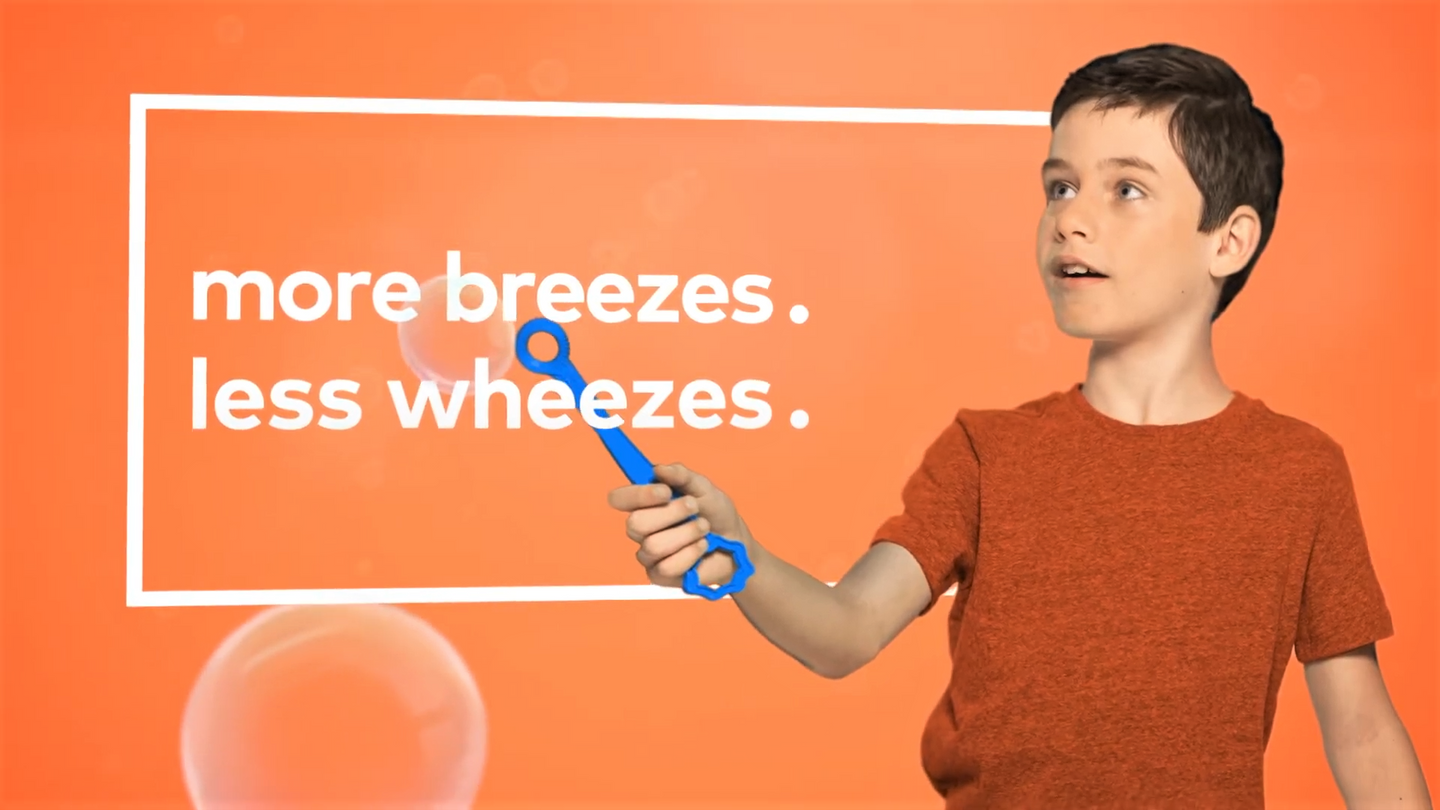 Boy making bubbles with the words "More breezes, less wheezes" displayed.